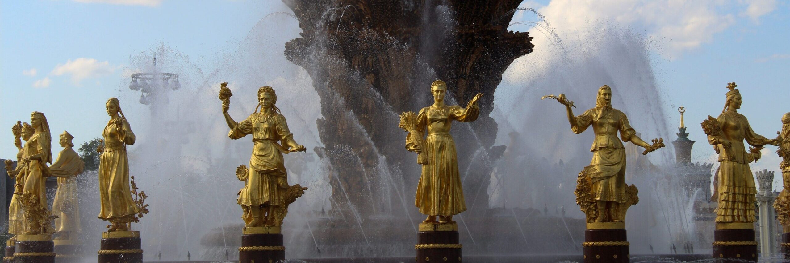 Stunning fountain with golden statues under a blue sky at VDNKh, showcasing artistic craftsmanship.